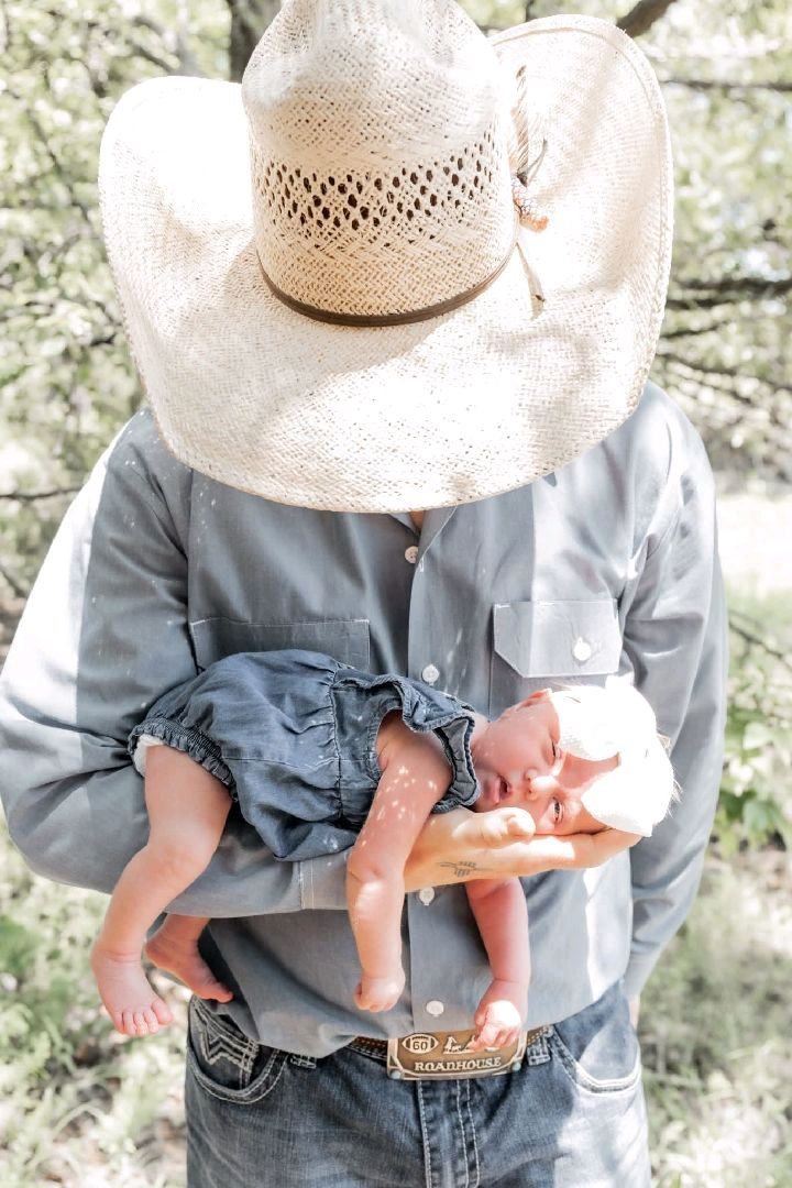 Father in cowboy hat holding newborn daughter
