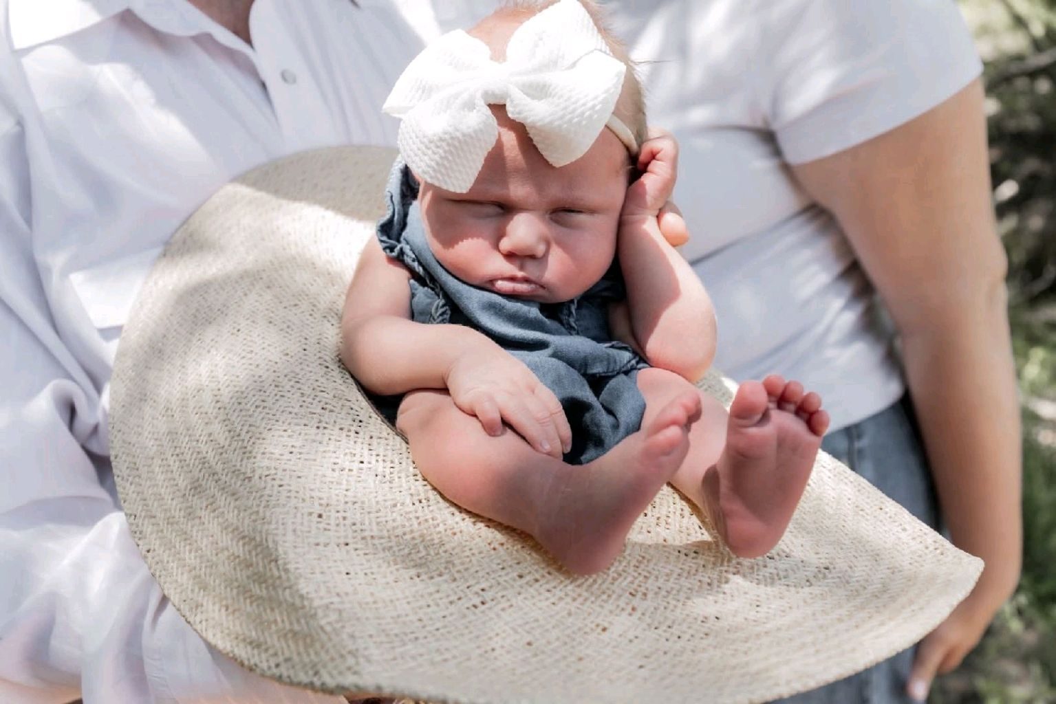 Newborn cradled in straw hat during outdoor couples session — LA Photography Oklahoma