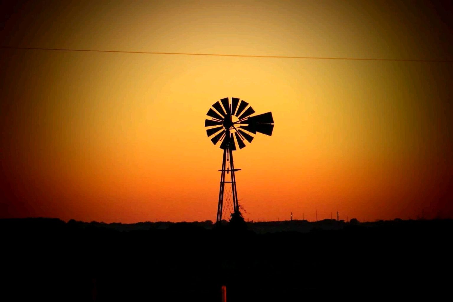 Farm windmill silhouetted against an orange Oklahoma sunset